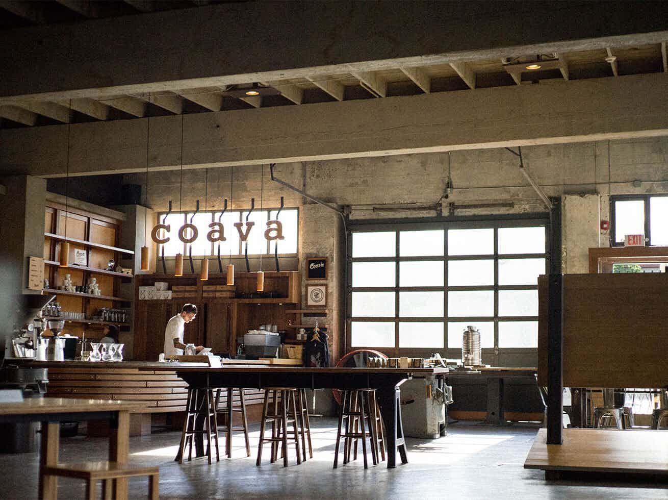Modern café interior with wood paneling, industrial lighting, and a sleek coffee bar.